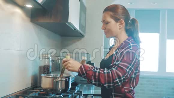 漂亮的女人在厨房里烹饪和测试食物女孩在室内倒磨碎的胡椒汤准备食物防止视频的预览图