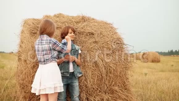 快乐的男孩和女孩在田里玩干草堆视频的预览图