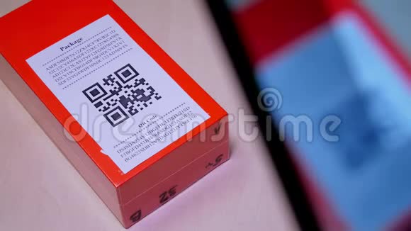 智能手机扫描橙色包裹或包裹盒上的纸质标签上的QR代码视频的预览图