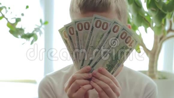 在金钱树的背景下快乐的男孩留下了100美元的钞票视频的预览图