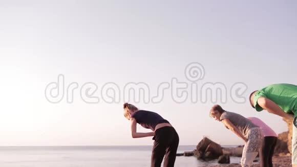 瑜伽课上一对成年女性和一名男性在海滩上与教练一起练习瑜伽和做呼吸练习视频的预览图
