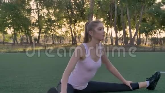 年轻漂亮的女人在公园的足球场上伸展晨练健身模特锻炼视频的预览图