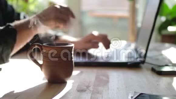一个男人用鼠标和键盘上网喝热茶把注意力集中在杯子上视频视频的预览图