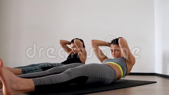 两个女人躺在你的背上用腿抬起做仰卧起坐照相机的总体计划在前进视频的预览图
