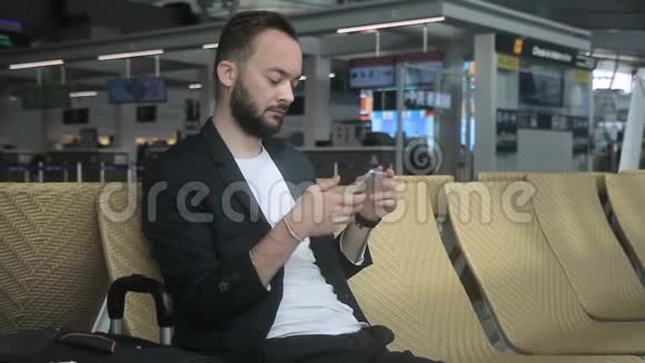 年轻人坐在机场大楼里用电话视频的预览图