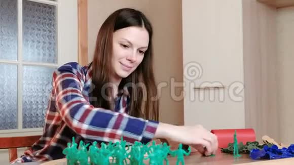 女人用木铁路把不同颜色的塑料士兵放在桌子上视频的预览图