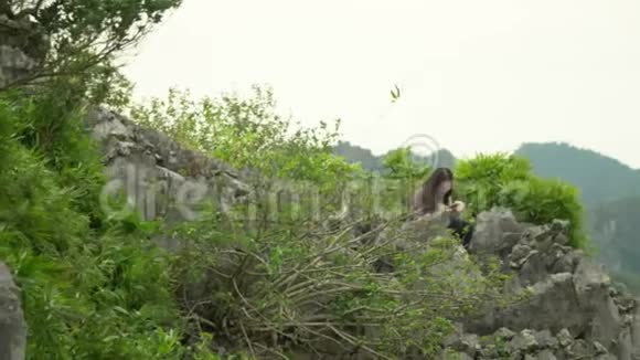 女孩坐在猴子岛上的岩石上那个长发女孩在电话里通过照片竖起大拇指岛屿视频的预览图