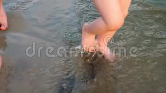 宝贝沿着河岸走第一步在两边泼水和他的母亲一起走腿特写视频的预览图