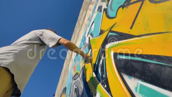 涂鸦艺术家正在墙上画一个黄色的字母从下面看视频的预览图