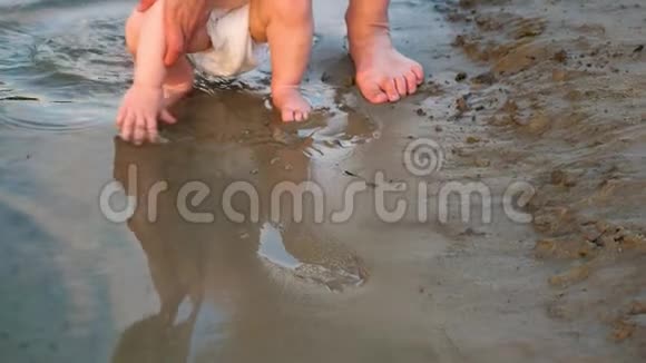 宝宝在沙滩上手拉手玩水四周泼水和妈妈一起散步腿特写镜头慢动作视频的预览图
