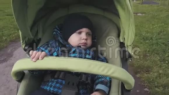 一个穿暖和衣服的小男孩骑在婴儿车里视频的预览图