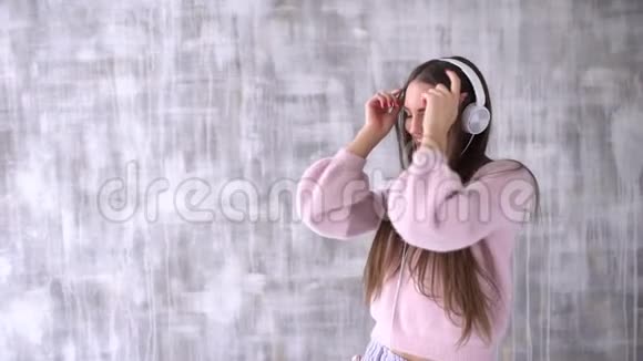 女孩喜欢音乐戴着耳机的女孩用手机在灯光背景下跳舞慢动作视频的预览图