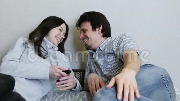 两个人躺在沙发上看电视男人和女人互相看着微笑着视频的预览图