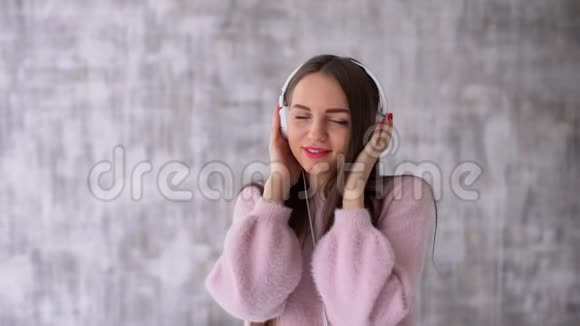 年轻女孩玩得开心用耳机听音乐的肖像慢动作视频的预览图