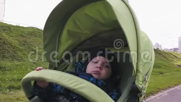 一个穿暖和衣服的小男孩骑着婴儿车视频的预览图