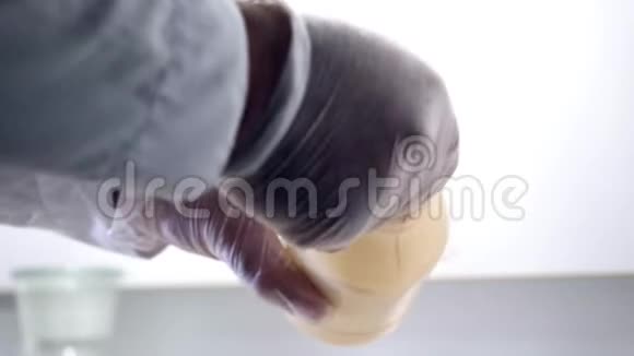 实验室工作人员使用天平化学家戴着手套把流沙放在玻璃杯上视频的预览图