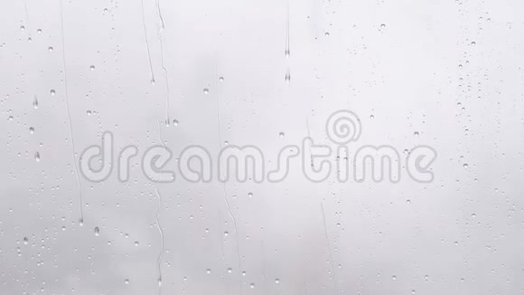 夏季雨水落在窗户玻璃上慢动作4k镜头大雨落在白色模糊背景下视频的预览图