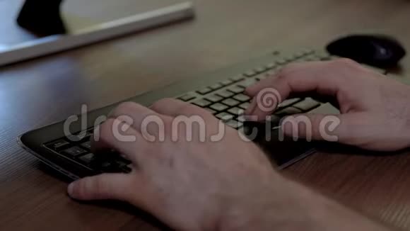 男人手的特写快速地在键盘上打字木制桌子视频的预览图