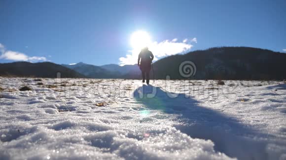 在阳光明媚的日子里带着棍子在雪地上爬上徒步旅行者无法辨认在雪地里散步的年轻男性游客视频的预览图