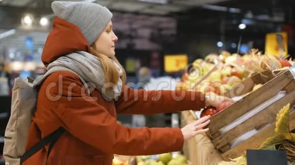 美丽的运动女孩正在超市挑选水果摊上的苹果视频的预览图