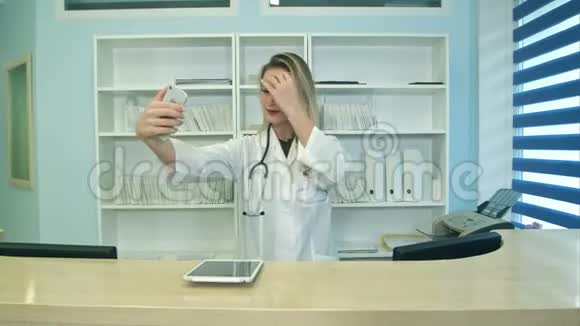 微笑的女医务工作者在前台用手机自拍视频的预览图