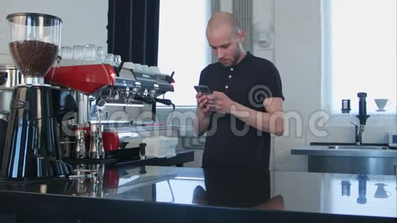 男性咖啡师在工作场所使用智能手机视频的预览图