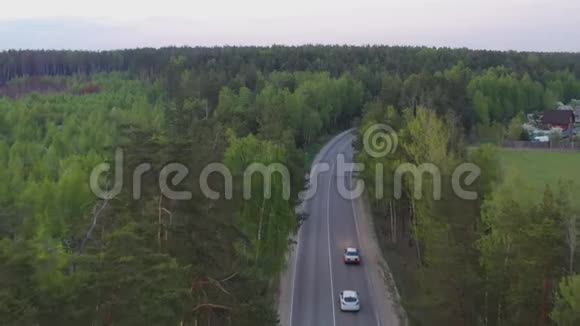 从空中俯瞰蜿蜒于树木之间的乡村道路视频的预览图
