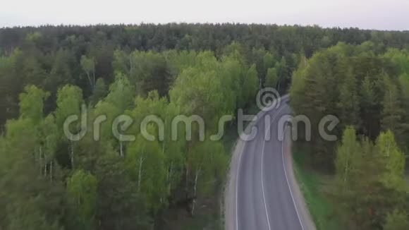 从空中俯瞰蜿蜒于树木之间的乡村道路视频的预览图