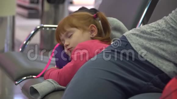 在机场候机区睡觉的女孩和妈妈航班延误视频的预览图