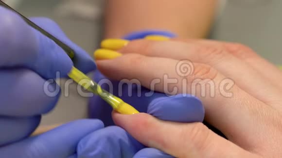 在指甲上涂上涂黄油的特写美容院手工美甲工艺视频的预览图