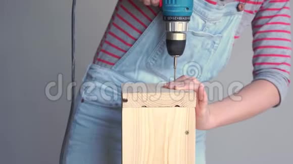 一个女人做一个非女人的工作用螺丝刀在木箱里钻一个洞视频的预览图