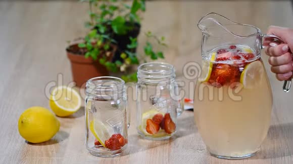 草莓柠檬水加冰在梅森罐子上的木制桌子视频的预览图