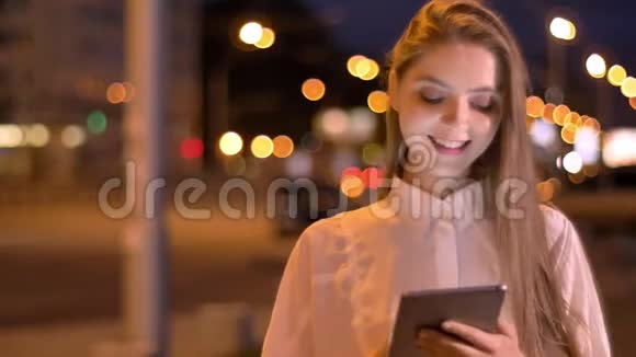 年轻可爱的女孩正在夏天晚上的平板电脑上输入信息交流观念视频的预览图