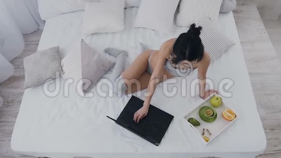 上图是一个年轻漂亮的短发女孩穿着内衣长袜和笔记本电脑坐在床上自由职业的视频的预览图