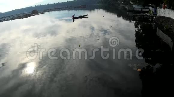 太阳升起在湖上船夫划着桨朝污染的湖岸走去剪影式视频的预览图