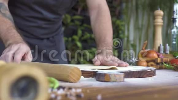 用滚筒在木板上做馅饼把薄面团煮熟用擀面杖在桌子上擀制酵母面团视频的预览图