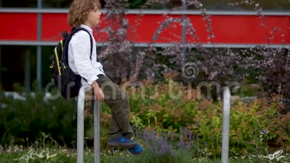 一个悲伤的男孩坐在学校附近院子里的栏杆上那个小学生起来伤心地走了心理视频的预览图