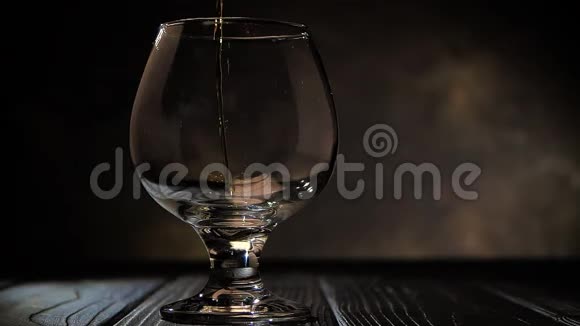白兰地被倒进玻璃杯里在黑暗的背景下视频的预览图