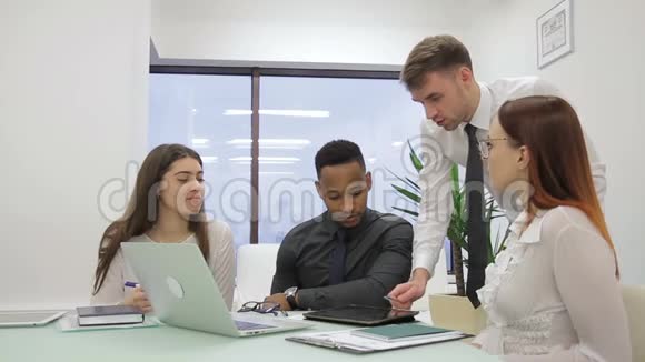 年轻员工与领导公司的笔记本电脑在餐桌上交流视频的预览图