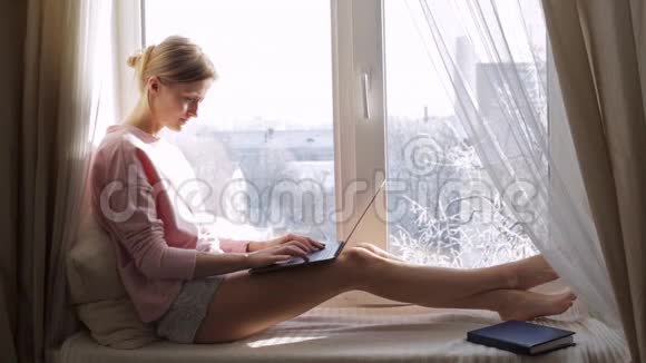 冬天天气晴朗有笔记本电脑的女人坐在窗台上视频的预览图