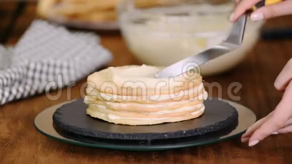 在家里做一层一层的拿破仑蛋糕把奶油蛋糕放在烘焙的糕点上视频的预览图