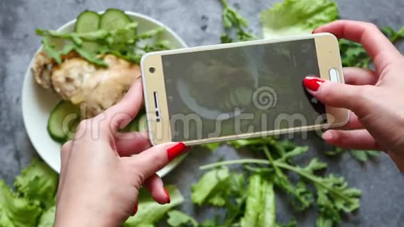 女孩博主在智能手机上为社交网络制作照片菜肴特写镜头平躺照片视频的预览图