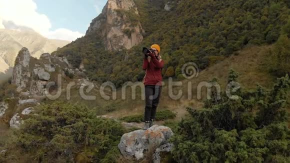 女摄影师戴着一顶帽子带着相机在山上散步北高加索地区视频的预览图