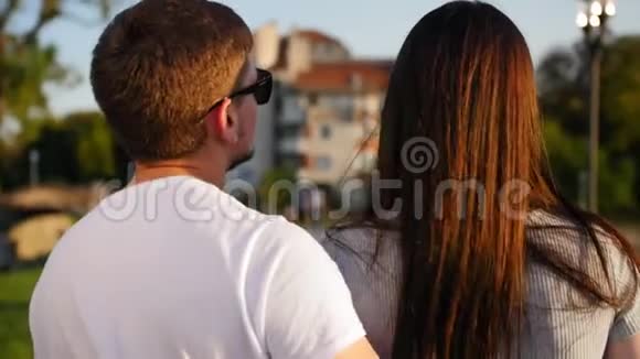 靠近美丽迷人的年轻夫妇在公园散步的后景后方户外活动视频的预览图