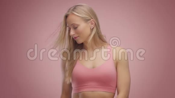 粉红背景工作室里的金发模特头发吹在空中视频的预览图