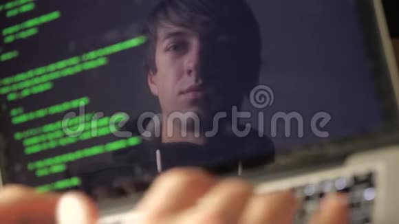 双重曝光戴眼镜的黑客在笔记本电脑上工作程序员在监视器中写入绿色代码反射视频的预览图