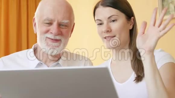 老人和女儿在家里通过笔记本电脑上的messenger应用程序进行视频聊天微笑挥手视频的预览图