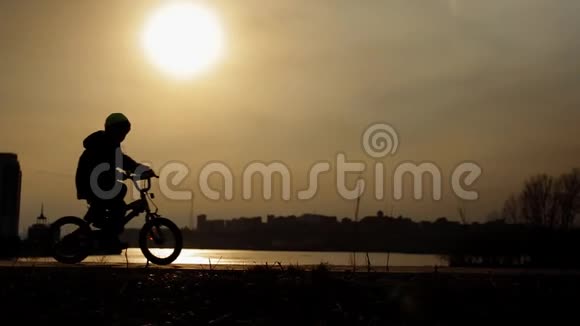 一个男孩在公园里骑自行车的剪影视频的预览图