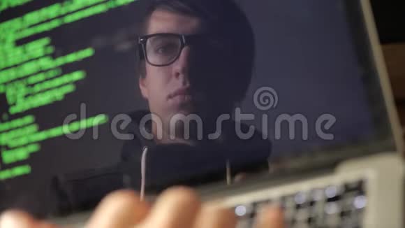 双重曝光戴眼镜的黑客在笔记本电脑上工作程序员在监视器中写入绿色代码反射视频的预览图