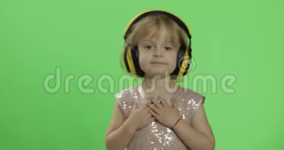 女孩穿着光滑的衣服和耳机听音乐和跳舞色度键视频的预览图